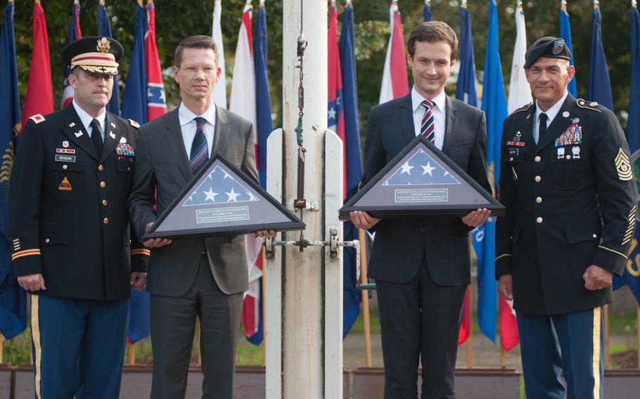 U.S. Army Garrison Ansbach commander Col. Christopher Benson and Command Sgt. Maj. Mark Kiefer flank the Schweinfurt Lord Mayor Sebastian Remelé and the Schweinfurt county commissioner, Florian Topper, each holding one of the final American flags to be flown over the Schweinfurt military base, Sept. 19, 2014.