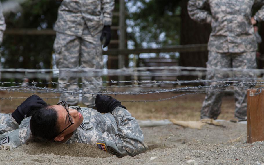 A soldier with 16th Combat Aviation Brigade, 7th Infantry Division, Joint Base Lewis-McChord, Wash., makes her way through a barbed-wire obstacle during the Sisters in Arms confidence course onSept. 19, 2014.