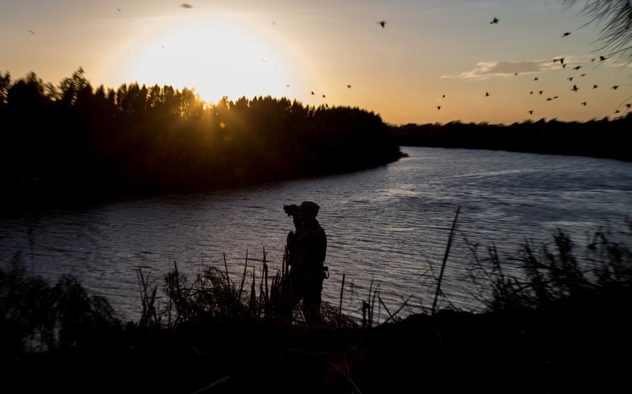 A soldier from the 36th Infantry Division, Texas Army National Guard observes a section of the Rio Grande River at sunset on September 2014. He is serving at the Texas-Mexico border in support of Operation Strong Safety.