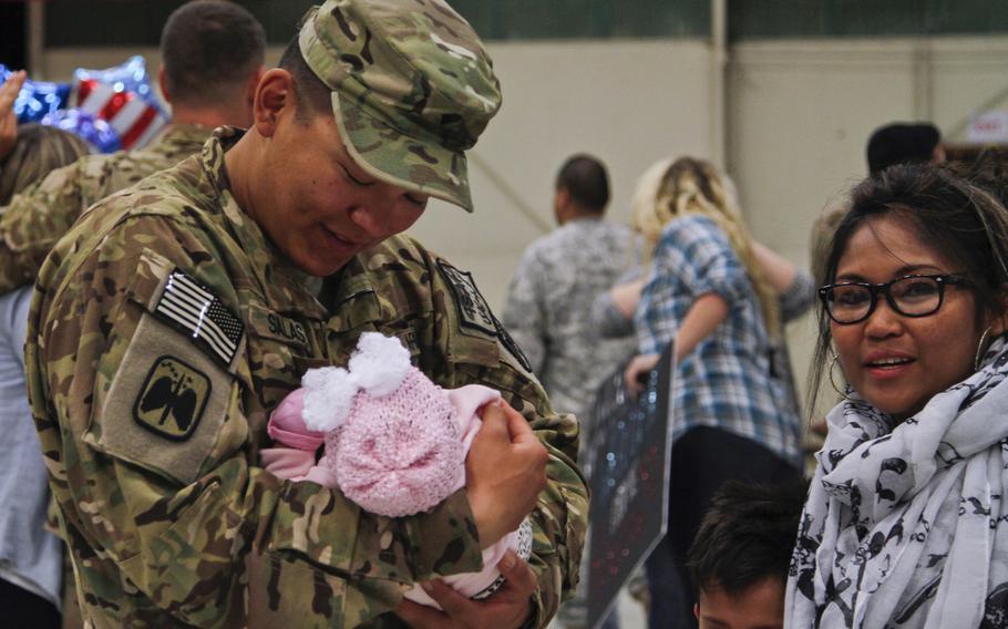 Spc. Kevin Salas of the 16th Combat Aviation Brigade holds his daughter, Alannah, for the first time at a homecoming ceremony on Joint Base Lewis-McChord, Wash., Sept. 20, 2014.