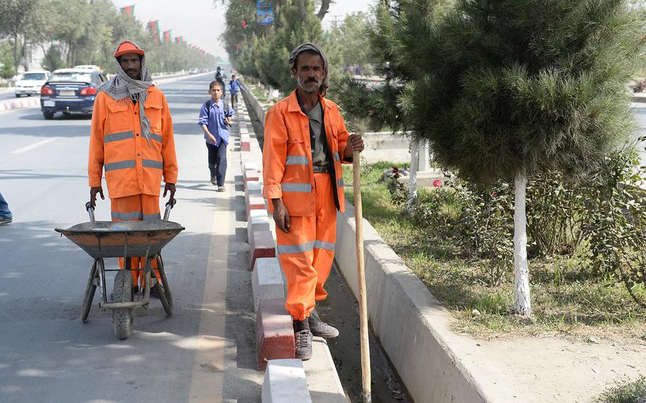 Street cleaning crews dot Airport Road in Kabul on Sunday, Sept. 28, 2014, a day ahead of presidential inauguration ceremony.