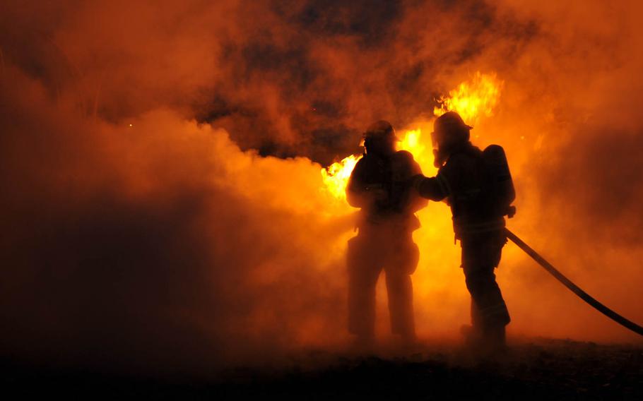 Tech. Sgt. Eric Barlow, 86th Civil Engineer Squadron fire station captain, and Airman 1st Class Kevin Williams, 86th CES firefighter, train on a simulated aircraft fire at Ramstein Air Base, Germany. The imagery was captured on June 18, 2014, as part of a multimedia project titled, "Day in the Life of the 86th Airlift Wing" showing how the wing supports multiple Air Force, joint and international missions daily.