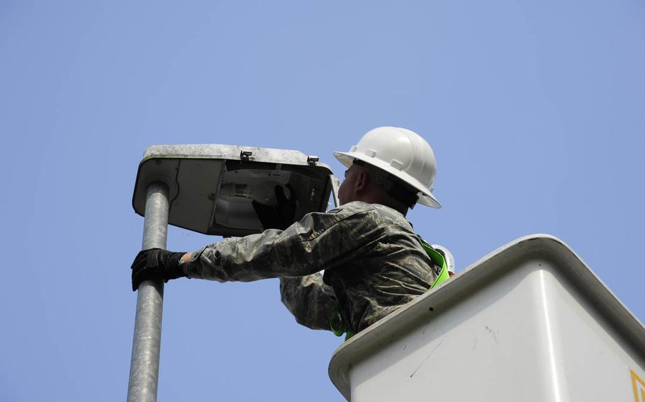 An electrician assigned to the 86th Civil Engineer Squadron prepares to change burned-out light bulbs from a base street light, while also checking for adequate voltage, on June 18, 2014, at Ramstein Air Base, Germany.