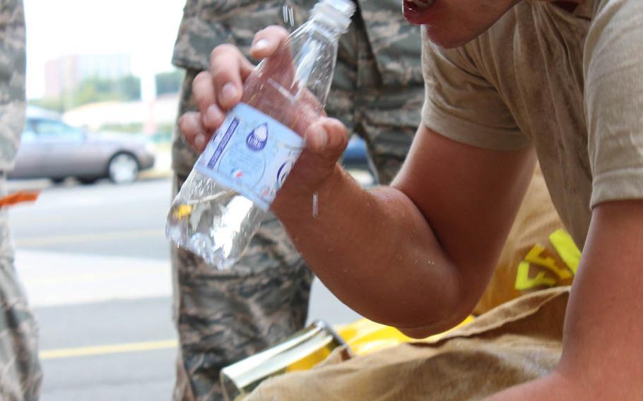 Airman Alexander Garratt, 86th Civil Engineer Squadron firefighter, hydrates as he doffs his gear upon completion of a confidence course run in full fire-fighting equipment at Ramstein Air Base, Germany, on June 18, 2014.