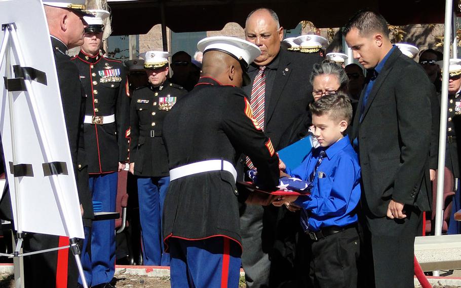 A Marine presents Jeremy Diaz, 8, with a flag at Camp Pendleton, Calif., on Nov. 25, 2014. Jeremy's father, Staff Sgt. Christopher Diaz, was killed in an IED explosion in Helmand province, Afghanistan, in 2011 and was awarded the Bronze Star with V in a ceremony at 1st Marine Special Operations Battalion, Marine Special Operations Command.