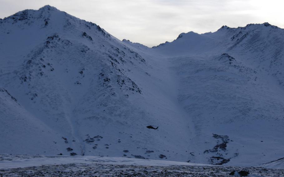 An Alaska Army National Guard UH-60 Black Hawk helicopter is dwarfed by mountains near Anchorage, Alaska, on Feb. 13., 2015. It's essential that the chopper's crewmembers learn cold-weather survival skills in case they are forced to make an emergency landing. 