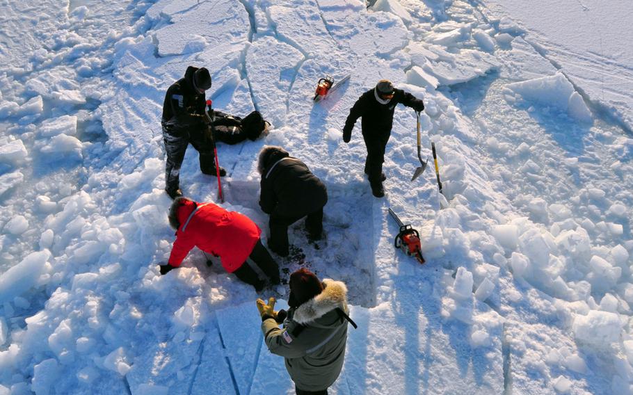 Members of the Applied Physics Laboratory Ice Station clear ice from the hatch of the Los Angeles-class submarine USS Annapolis after the sub broke through the ice while participating in Ice Exercise 2009 in the Arctic Ocean. The crews of the Annapolis and the Los Angeles-class attack submarine USS Helena were learning to operate in the challenging and unique environment that characterizes the Arctic region.