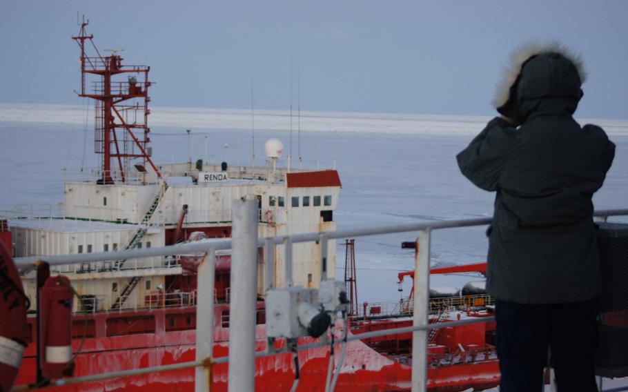 A Coast Guard Cutter Healy crewmember takes a moment to watch the Russian-flagged tanker Renda steam through the ice in the North Bering Sea while the cutter crew escorts the tanker to Nome on Jan. 6, 2012.