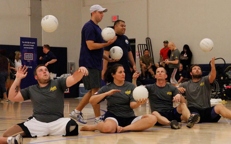 Athletes demonstrate their serving skill while sitting during the 1st day of trials at Joint Base Pearl Harbor-Hickam, Hawaii, for the Warrior Games to be held in June 2015. 'Seated' volleyball equalizes the playing ground for athletes with missing or injured legs.