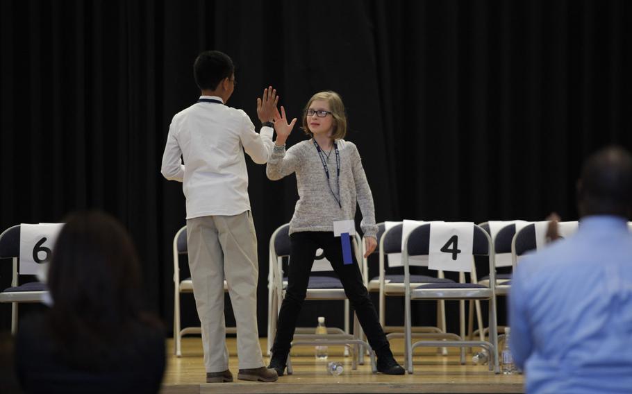 Grafenwohr Elementary School fourth-grader Ella Scheuermann and Naples sixth-grader Ryan Rayos high-five after Rayos properly spelled ''peloton'' to win the European PTA Spelling Bee Saturday, March 21, 2015, at at Ramstein Elementary School in Germany.
