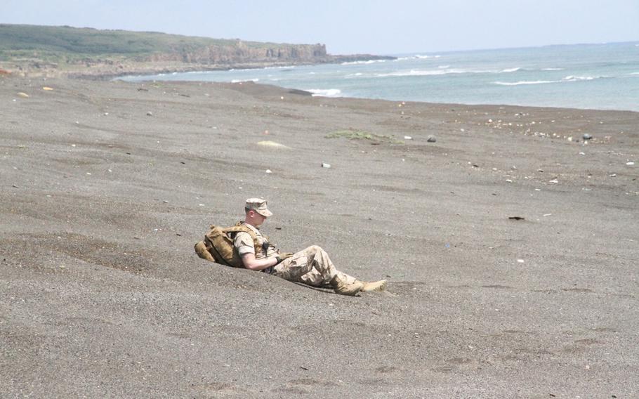 Navy corpsman Petty Officer 3rd Class Michael Vallet sits in the black Iwo Jima sands for a moment of solemn reflection during the 70th anniversary ceremony of the Battle of Iwo Jima on March 21, 2015.


