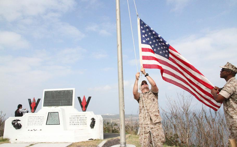 Marine 1st Lt. John Roberts, left, and Gunnery Sgt. Stephen Traynham raise a flag on Mount Suribachi near the spot of the iconic Iwo Jima flag raising following the ceremony marking 70 years since the battle.

