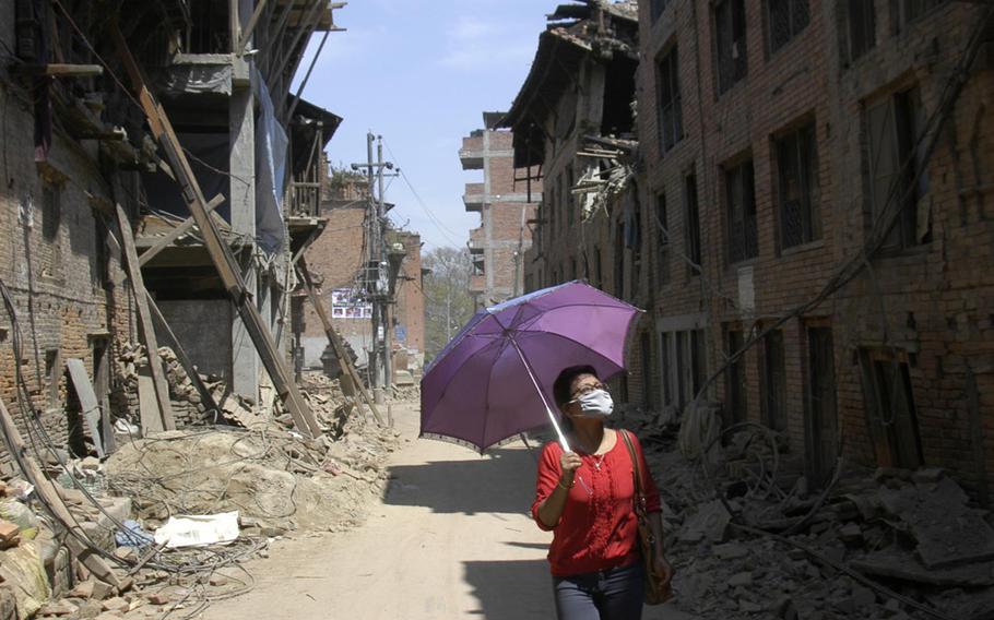A woman walks past earthquake-damaged buildings in Bhaktapur, Nepal, on Tuesday, May 5, 2015.