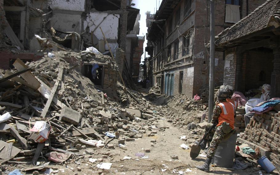 Soldiers watch debris fall from an earthquake-damaged building in Bhaktapur, Nepal, Tuesday, May 5, 2015.