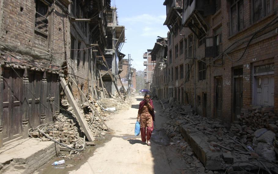 A woman walks past earthquake damaged buildings in Bhaktapur, Nepal, on Tuesday, May 5, 2015. The U.S. military planned to send 500 troops to Nepal as a follow-on force to the initial U.S. response to the April 25 earthquake.