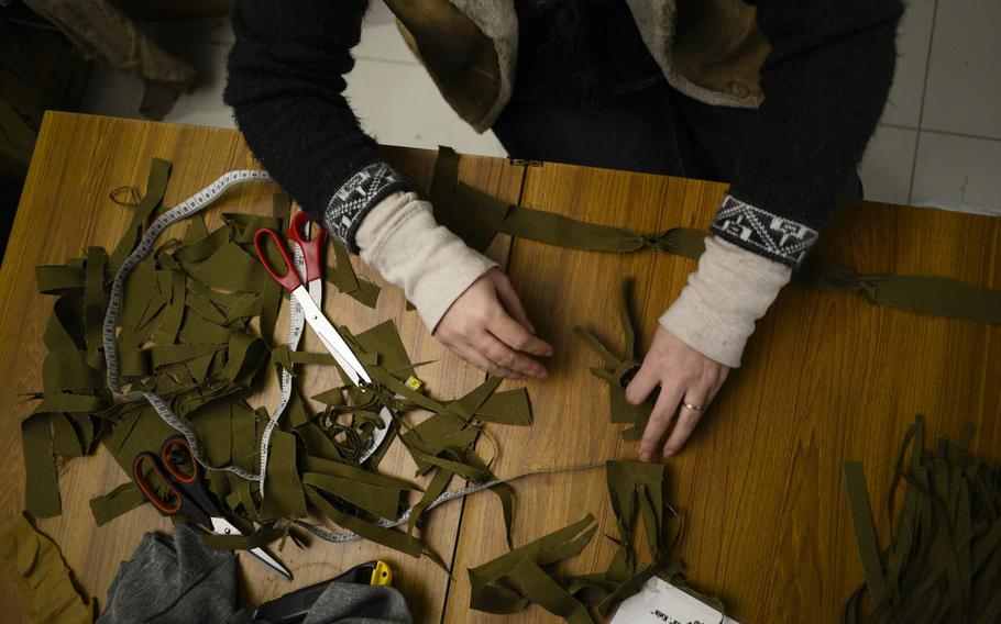 A volunteer in the Sitka, or Net Battalion, cuts strips of dyed material to make camouflage nets for Ukrainian soldiers fighting on the eastern front.