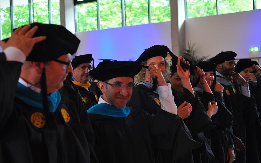 Graduates of the University of Maryland University College Europe move the tassels on their caps from right to left at the conclusion of Saturday's commencement ceremony on May 9, 2015, at the Gartenschau in Kaiserslautern, Germany.