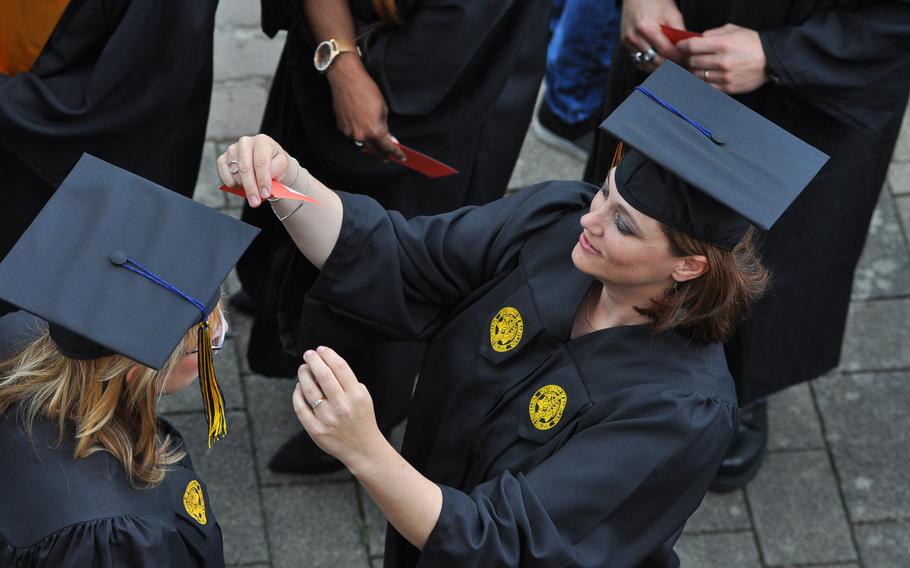 A University of Maryland University College Europe graduate adjusts the cap of a fellow graduate prior to the commencement ceremony at the Gartenschau in Kaiserslautern, Germany, on Saturday, May 9, 2015.