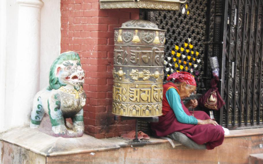 A Buddhist woman rests beside Boudhanath Stupa in Kathmandu, Nepal, Saturday, May 9, 2015.
