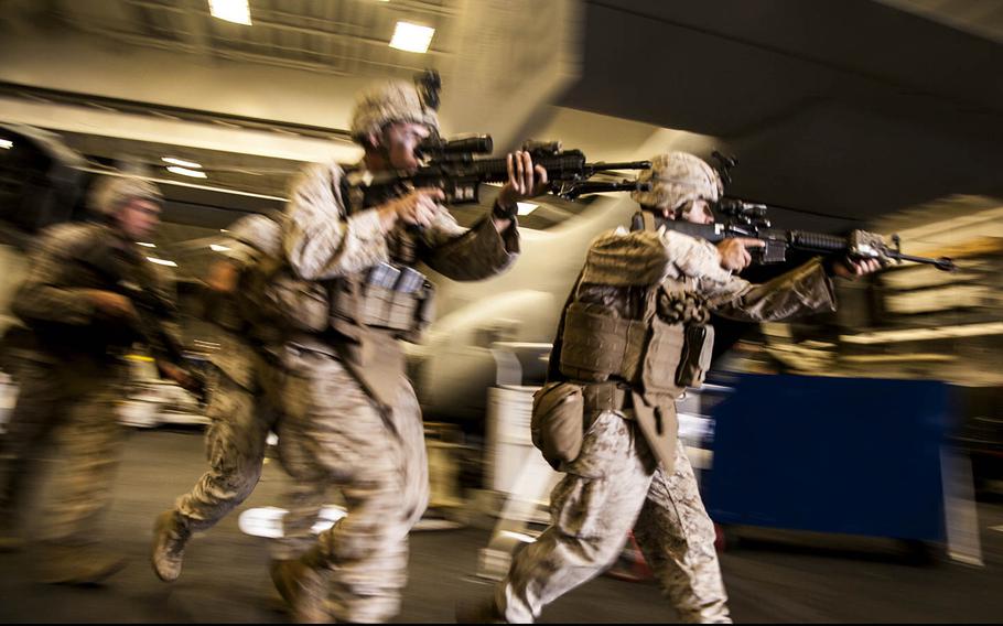 U.S. Marines with Battalion Landing Team 3rd Battalion, 1st Marine Regiment, 15th Marine Expeditionary Unit, rush toward their objective in the hangar bay of the USS Essex at sea in the Pacific Ocean, May 14, 2015.