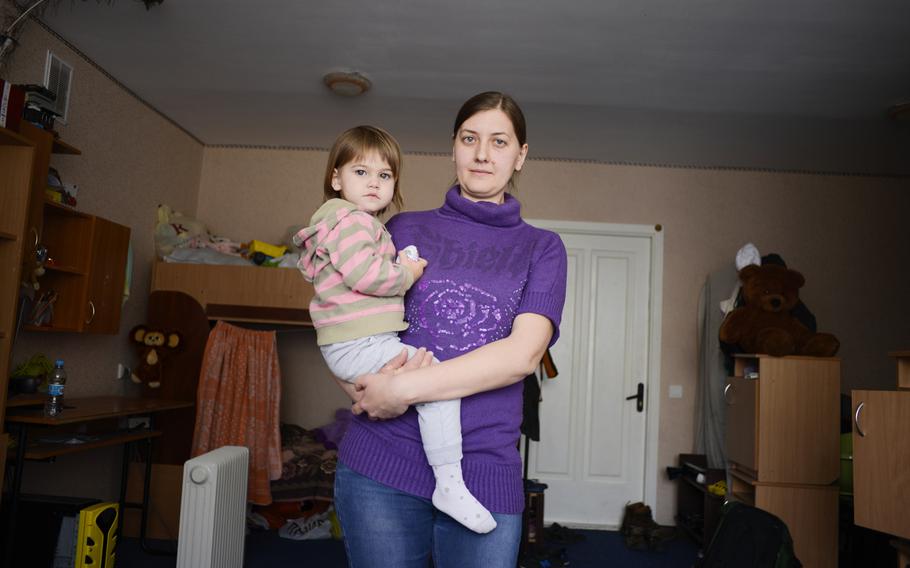 Iryna and her daughter, Victoriya, pose for a portrait in their one-room apartment at a center for people displaced by the war in eastern Ukraine. She lives in the apartment with her husband and older daughter, Vorsil, Ukraine, April 23, 2015.