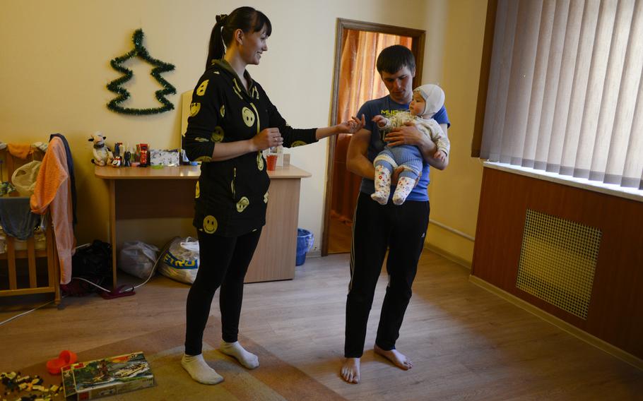 Nina Rusalkina, left, and her husband, Zhenya Kravchenko, play with their daughter, Danila, in their apartment at a retreat converted into housing for  displaced persons, Pushcha Vodytsya, Ukraine, April 23, 2015.