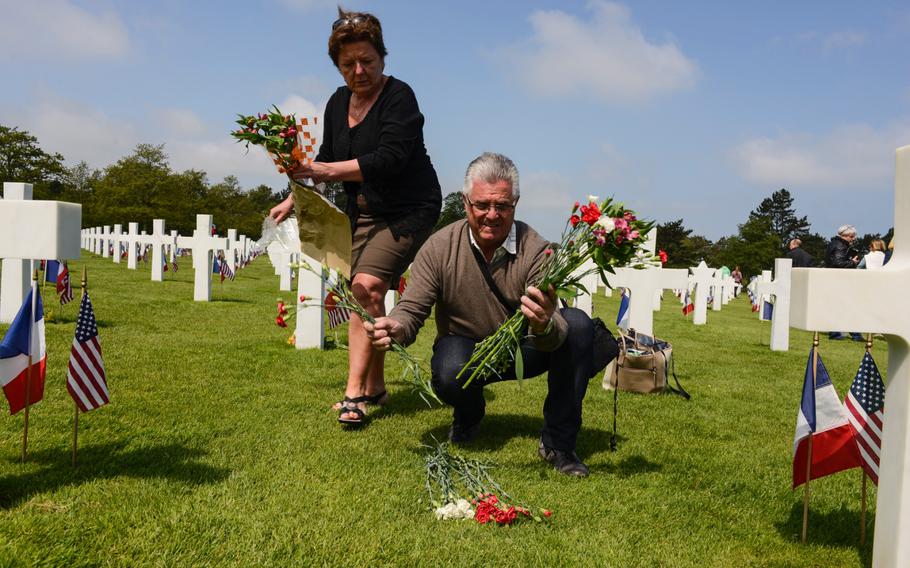 Lydie and Phillipe Pelcerf lay flowers to pay their respects after the Memorial Day ceremony at the Normandy American Cemetery, Sunday, May 24, 2015.