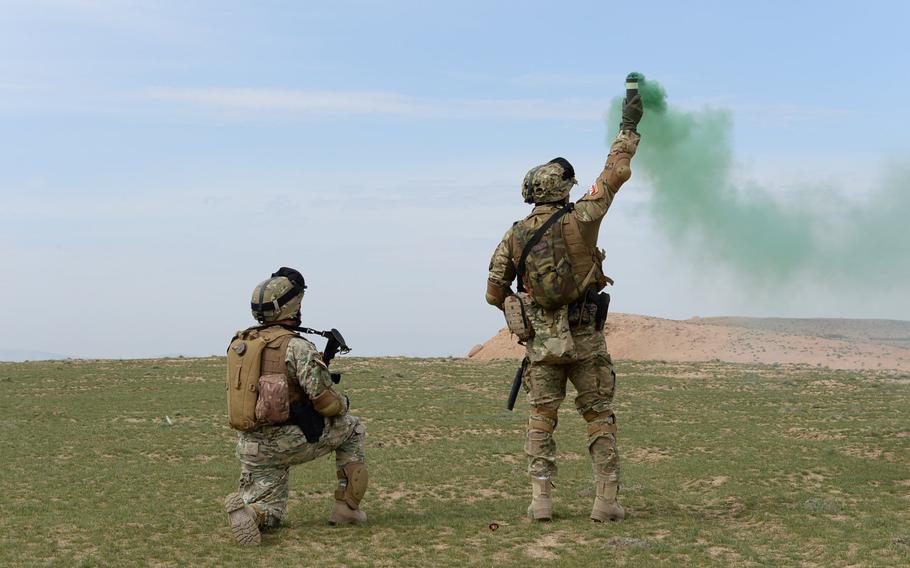 A member of the quick-reaction force at  Train, Advise and Assist Command-North sets off a smoke grenade to mark the landing zone for incoming helicopters during a March 31, 2015, NATO combat drill in Balkh province, northern Afghanistan.