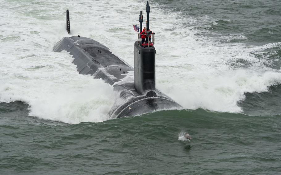 A dolphin jumps in front of the Virginia-class attack submarine Pre-Commissioning Unit John Warner as the boat conducts sea trials in the Atlantic Ocean on May 21, 2015.