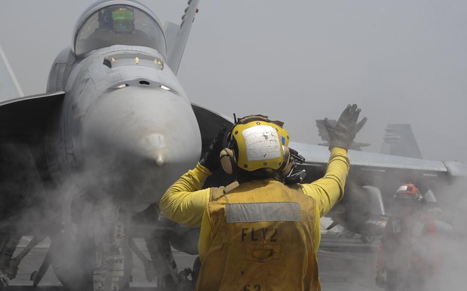 A Sailor guides an F/A-18E Super Hornet assigned to Strike Fighter Attack Squadron 136 along the catapult tracks on the flight deck of the USS Theodore Roosevelt on May 30, 2015 in the Mediterranean Sea.