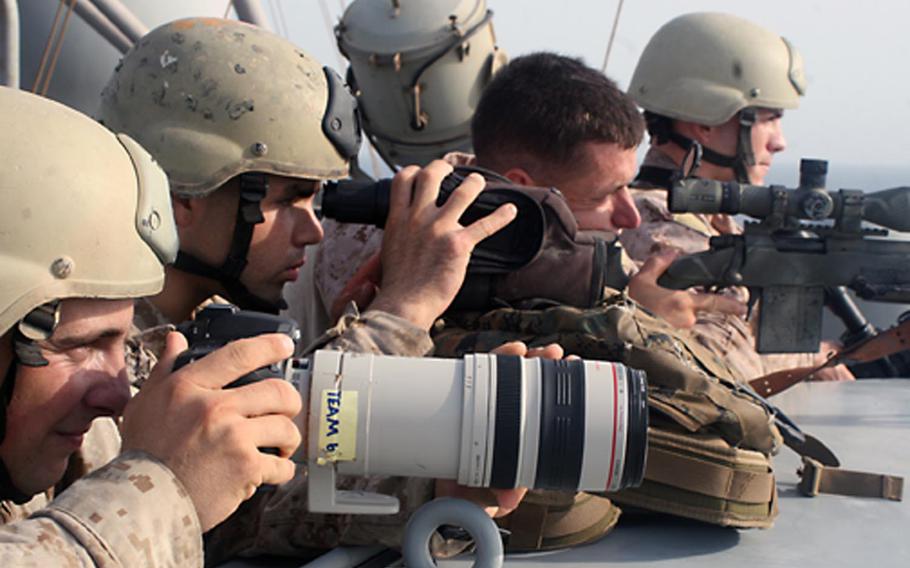 In this image taken by combat camera personnel, U.S. Marine Corps snipers provide cover and observation during a boarding and seizure operation to recover the Magellan Star from suspected pirates who took control of the ship in the Gulf of Aden on Sept. 9, 2010.  Combat camera troops get training in aerial, underwater, night-vision and low-light photography and videography


