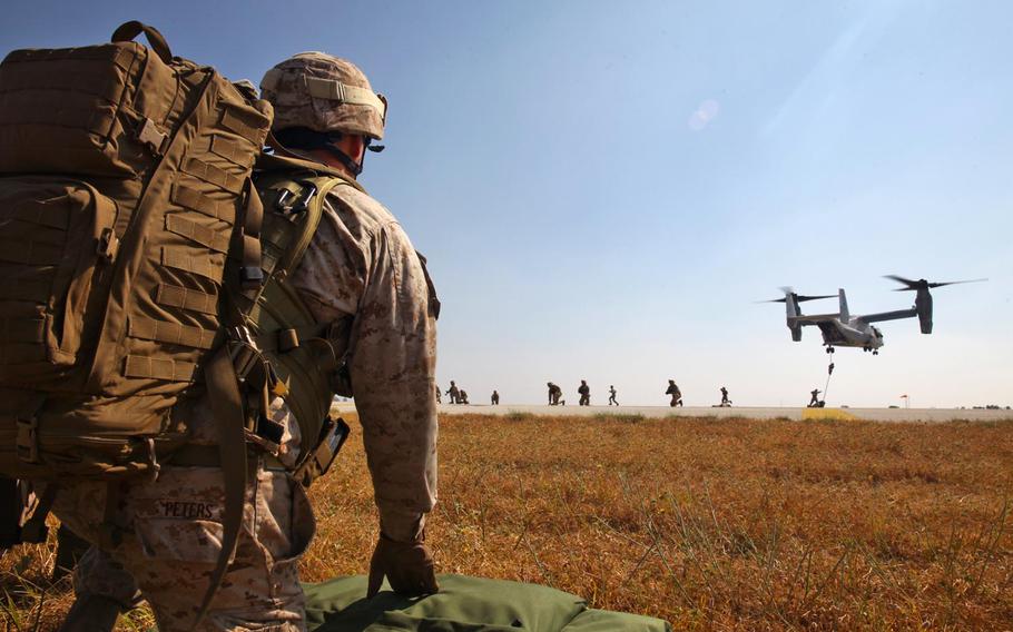 In this combat camera image, Petty Officer 2nd Class Nick Peters, a hospital corpsman with the Ground Combat Element of Special Purpose Marine Air-Ground Task Force Crisis Response, watches Marines conducting helicopter rope suspension techniques operations July 23, 2013, at Moron Air Base, Spain. There are 700 active-duty troops and more than 240 reserve personnel assigned to combat camera units in the Army, Navy and Air Force or spread throughout other units in the Marine Corps  