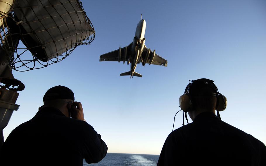 Seaman Chris Cardenas, left, and Boatswain's Mate Seaman Guillermo Mercado, right, stand aft lookout watch on the fantail of the aircraft carrier USS John C. Stennis as an EA-6B Prowler from the ''Yellow Jackets''' of Electronic Warfare Squadron 138 comes in for an arrested landing January 17, 2009.