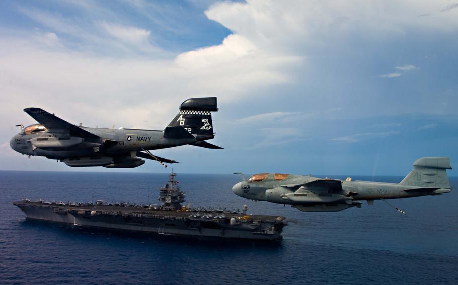 Two EA-6B Prowlers assigned to the ''Rooks'' of Electronic Attack Squadron 137 fly in formation over the aircraft carrier USS Enterprise on October 15, 2012.