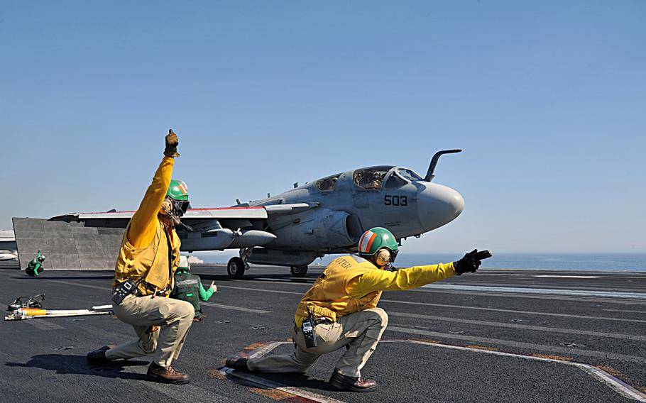 Lt. Robert Arndt, left, and Lt. Christopher Cannon, right, give the signal to launch an EA-6B Prowler assigned to the ''Garudas'' of Electronic Attack Squadron 134 off the flight deck of the aircraft carrier USS George H.W. Bush on June 19, 2014.