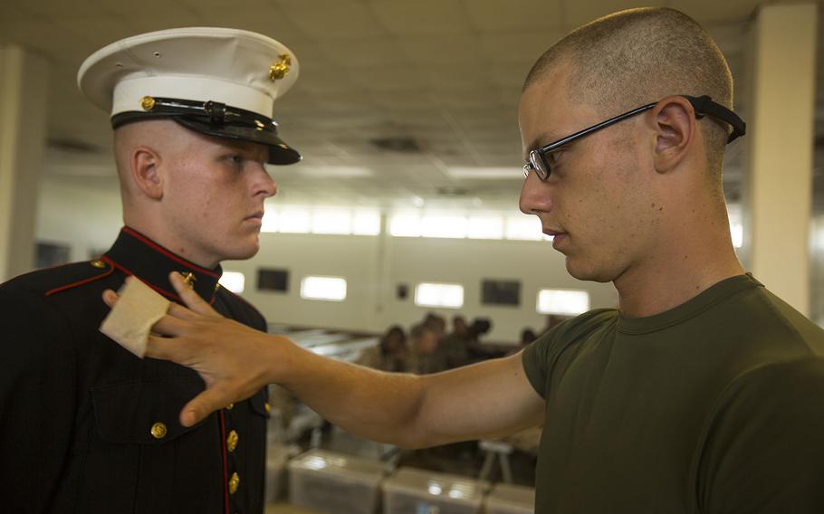 Recruit Robert J. Reynolds removes lint from a fellow recruit?s uniform before his boot camp photo is taken July 8, 2015, on Parris Island, S.C.