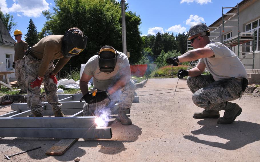 A Latvian soldier teaches Staff Sgt. John Burgh and Staff Sgt. Jason Loscar how to weld at the Naujene Orphanage, Latvia, on Monday, June 29, 2015. Burgh and Loscar are members of the 171st Air Refueling Wing Engineer Squadron team working on a humanitarian civic assistance project in Latvia.