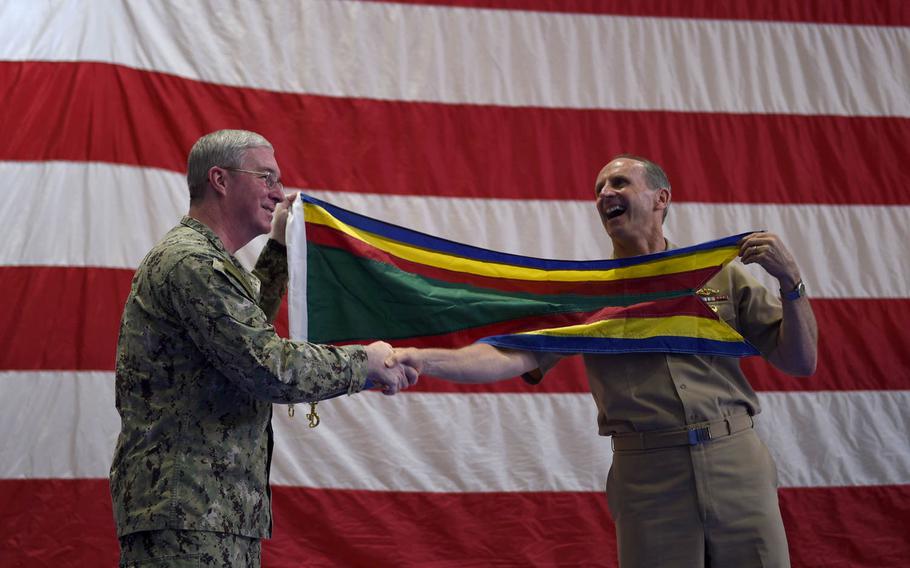 Vice Adm. John Miller, commander of U.S. Naval Forces Central Command and U.S. 5th Fleet, left, shares a laugh and shakes hands with Chief of Naval Operations Adm. Jonathan Greenert, right, after receiving the Navy Unit Commendation on behalf of his command during an all-hands call in Bahrain Monday, July 13, 2015.
