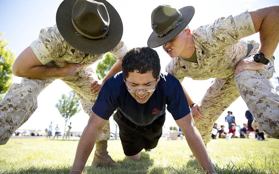 Sgts. Stephen Wills, left, and Brandon Hendrix, drill instructors from Marine Corps Recruit Depot San Diego, motivate Jose Garcia, a Marine enlistee from Yakima, Wash., during a Recruiting Station Seattle pool function at the Yakima Training Center in Yakima, July 17, 2015.