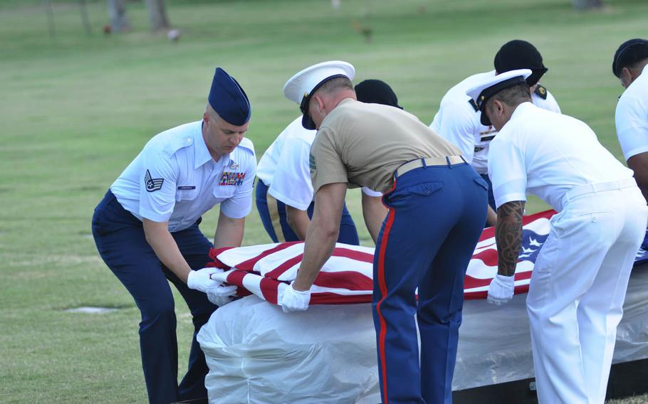 Servicemembers drape a flag over one of five caskets taken from the National Memorial Cemetery of the Pacific Monday, July 27, 2015, during a dignified transfer ceremony. The caskets contain the remains of unknown sailors and Marines who died on the USS Oklahoma on Dec. 7, 1941, and were being transferred to the Defense POW/MIA Accounting Agency for identificaiton.