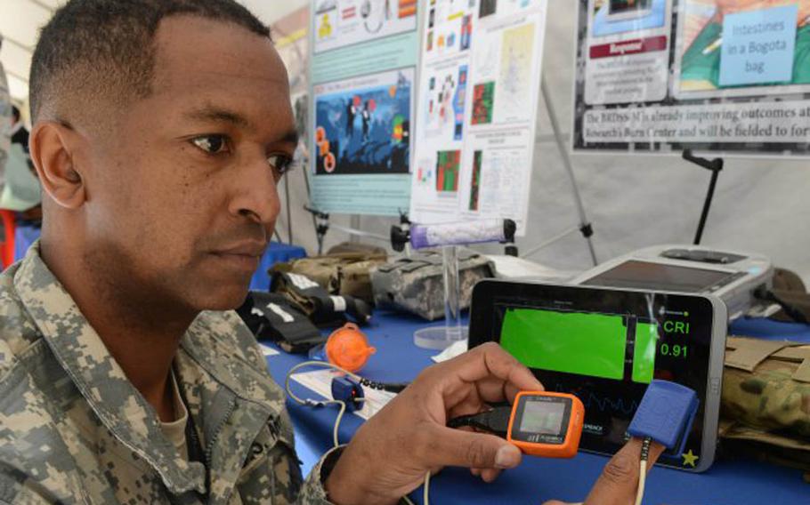 Lt. Col. Robert Carter, with the Tactical Combat Casualty Care Research program, shows the Compensatory Reserve Index, or CRI, device that could lower casualties on the battlefield by warning when shock is imminent due to blood loss. Behind the CRI is a green-screen smart tablet that can display results from multiple CRIs.
