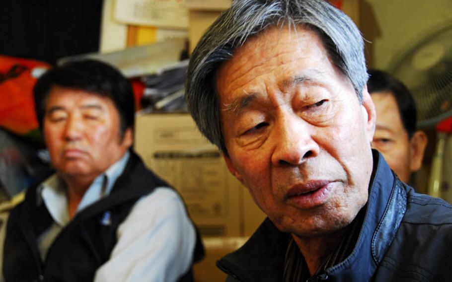 Jon Chon-bong, 78, sits inside a small building near Wolmi Park in 2011 and talks about the U.S. bombing of his village on Wolmi Island in 1950. He is one of 44 South Koreans who filed a lawsuit seeking compensation for the property their families lost in the bombing. Behind him, left, is Jeong Ji-eun, whose father died in the attack.