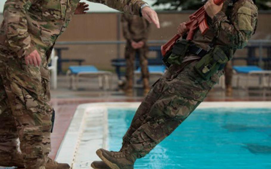 Master Sgt. Todd Boren and Staff Sgt. Gregory Carter, 5th Security Forces Squadron ranger assessment course cadre members, push Staff Sgt. Miguel Garcia, a 5th SFS member, into the pool for a water confidence exercise during pre-ranger training at Minot Air Force Base, N.D., on Wednesday, July 15, 2015.