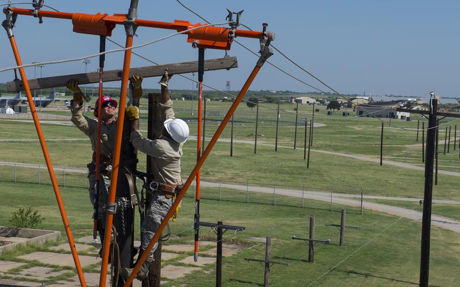 U.S. Air Force Staff Sgt. Andrew Goodrick, left, and Airman 1st Class Jaylen Wilkens, transferred power lines to a new pole by swapping out the cross arm and insulators at the 366th Training Squadron Hotline Training Course at Sheppard Air Force Base, Texas, on Friday, Aug. 7, 2015.