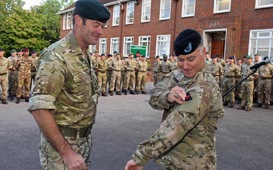 British army Maj. Gen. Patrick Sanders, 3rd (UK) Division commander, left, watches as U.S. Army Brig. Gen. Michael J. Tarsa attaches the division's tactical recognition flash to his uniform at a ceremony at Bulford Garrison, Wiltshire, England, Tuesday, Sept. 1, 2015. Tarsa took over as the deputy commander of the British division at the ceremony.