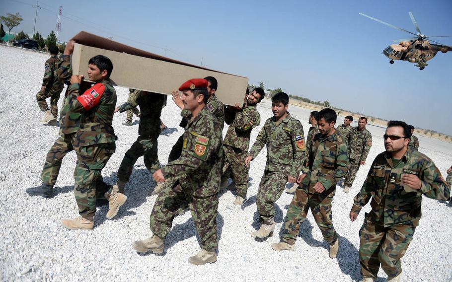 Afghan soldiers carry the coffin of a comrade, which was dropped off by helicopter at a base in Mazar-e-Sharif on Oct. 6, 2015. Helicopters shuttled supplies and casualties to and from battlefields across northern Afghanistan.