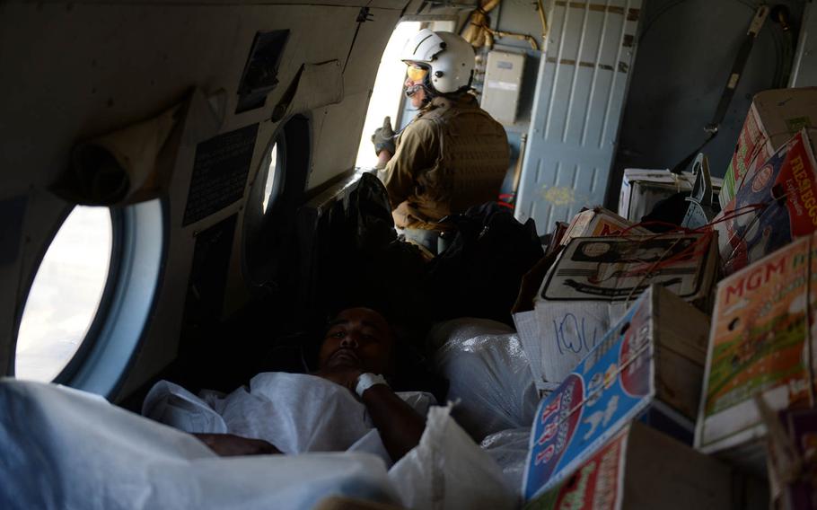 An injured soldier lies in an Afghan air force Mi-17 helicopter along with a load of apples and two coffins, Oct. 7, 2015. The apples would be dropped off at a garrison in Kunduz, while the wounded and dead soldiers were to be flown on to Kabul.