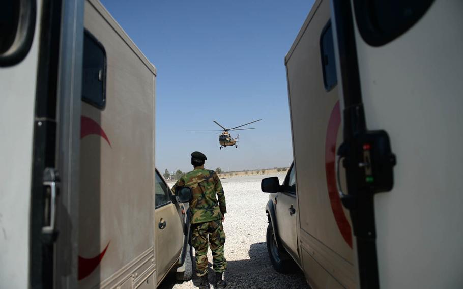 An army ambulance driver watches an Afghan air force helicopter land at a base in Mazsar-e-Sharif on Oct. 6, 2015. The ambulances were used to carry away injured and dead soldiers brought by the aircraft.