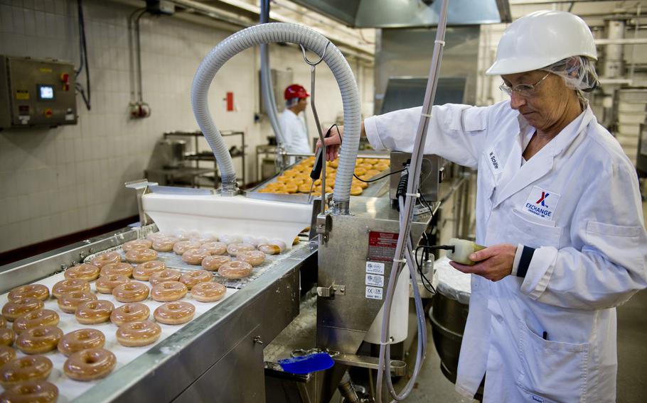 Marika Schaefer checks the Krispy Kreme doughnut icing temperature at the Exchange Bakery Europe in Gruenstadt, Germany, on Monday, Nov. 9, 2015. The doughnuts are produced with actual Krispy Kreme equipment and ingredients.