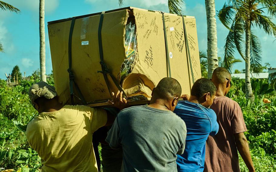 Men from Fais in the Federated States of Micronesia recover an airdropped box somewhere in the middle of their island Dec. 8, 2015.